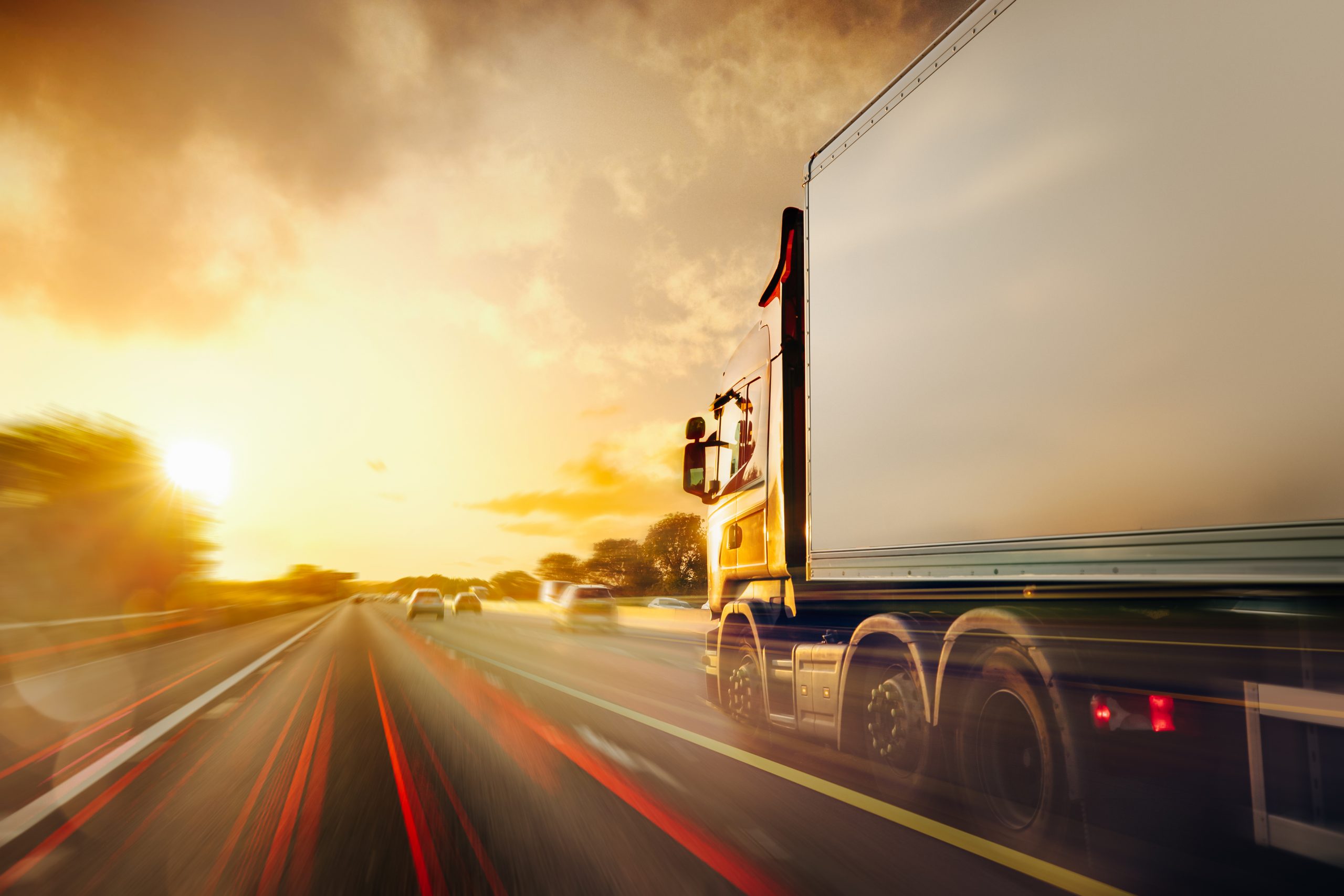Lorry driving at high speed on a motorway at sunset with motion blur.