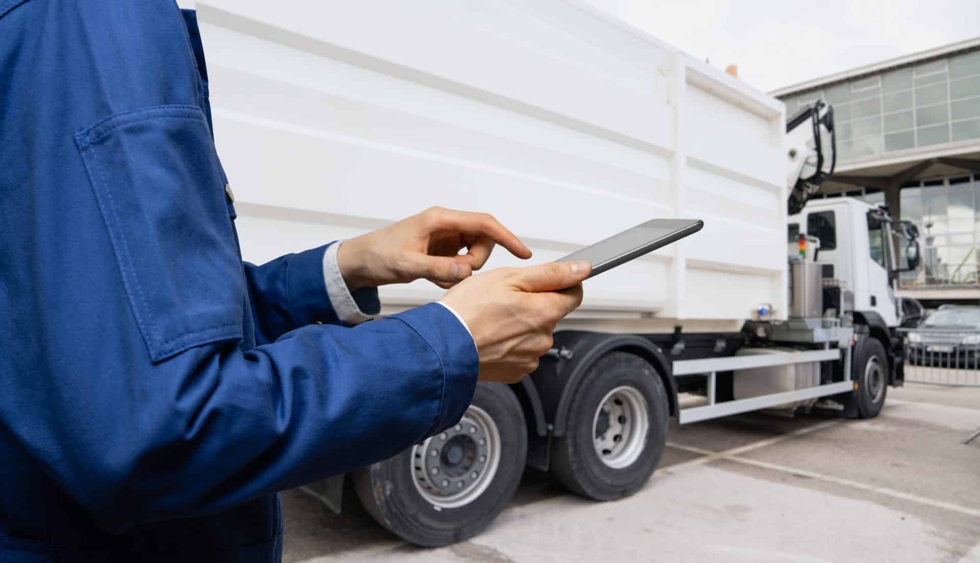 Man using his phone standing next to a white lorry with a building in front