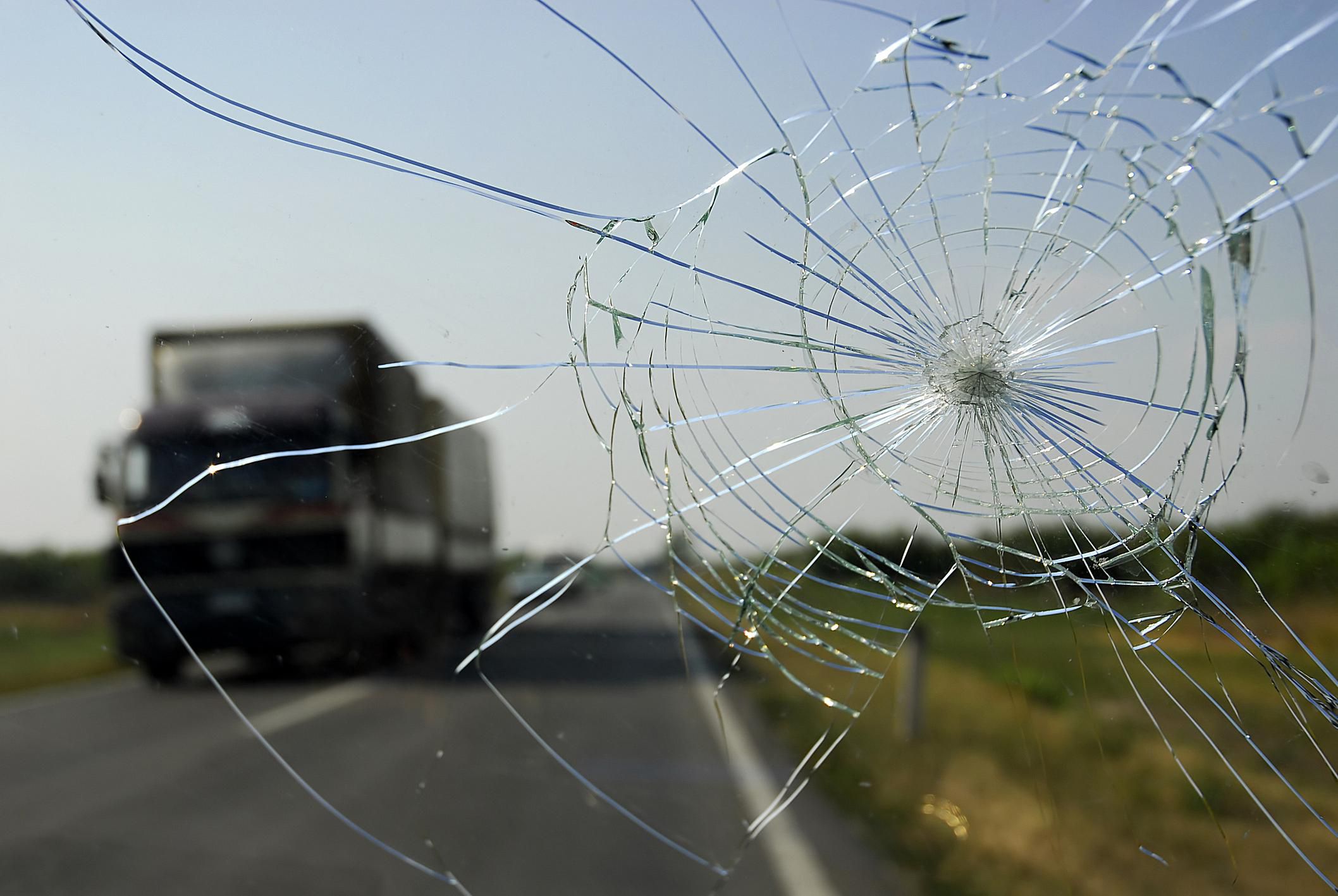 Cracked windscreen with a lorry in the background on a rural road.