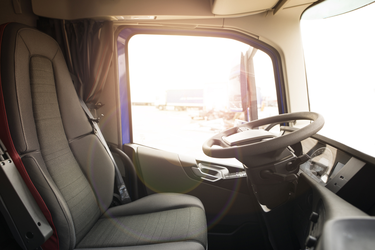Driver seat with steering wheel visible and sunlight streaming through the window