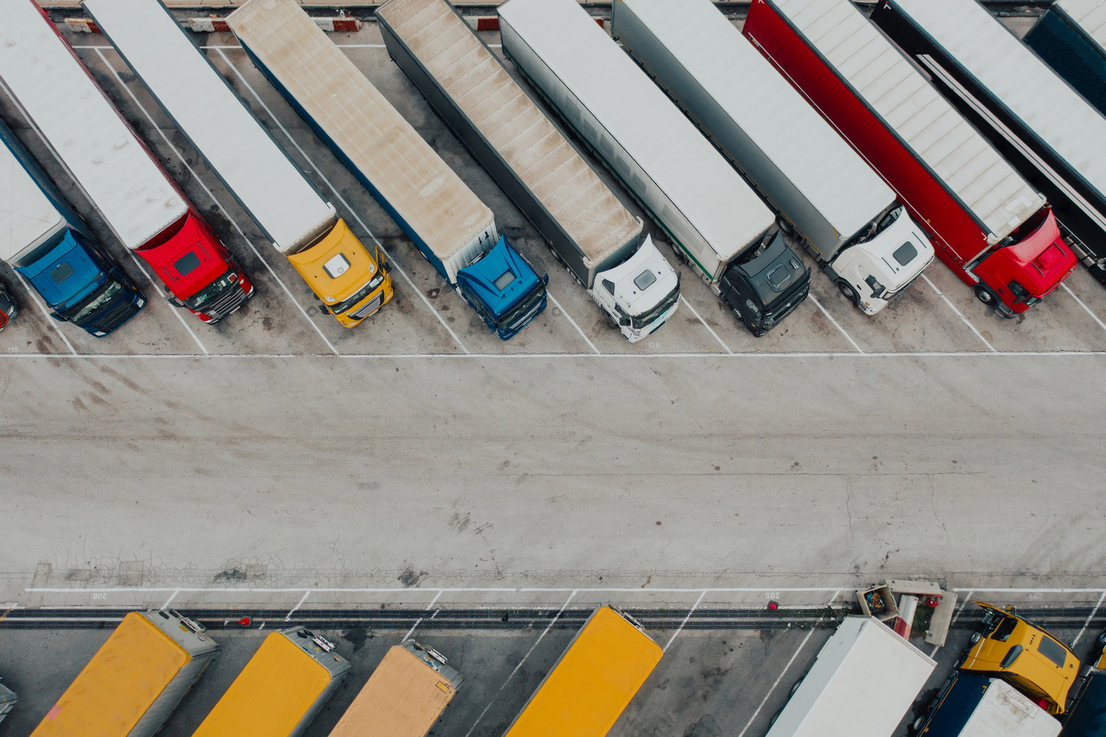 Aerial view of parked articulated lorries in various colours at a logistics depot.