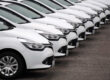 Row of identical white fleet cars parked diagonally in a lot.